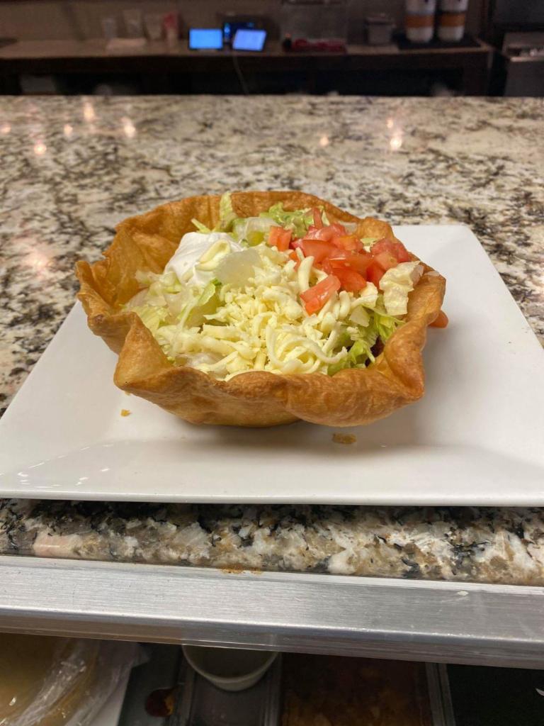 Taco Salad · A crispy flour tortilla bowl with beans, melted cheese, and your choice of shredded chicken or ground beef. Topped with lettuce, tomato, sour cream, and shredded cheese.
