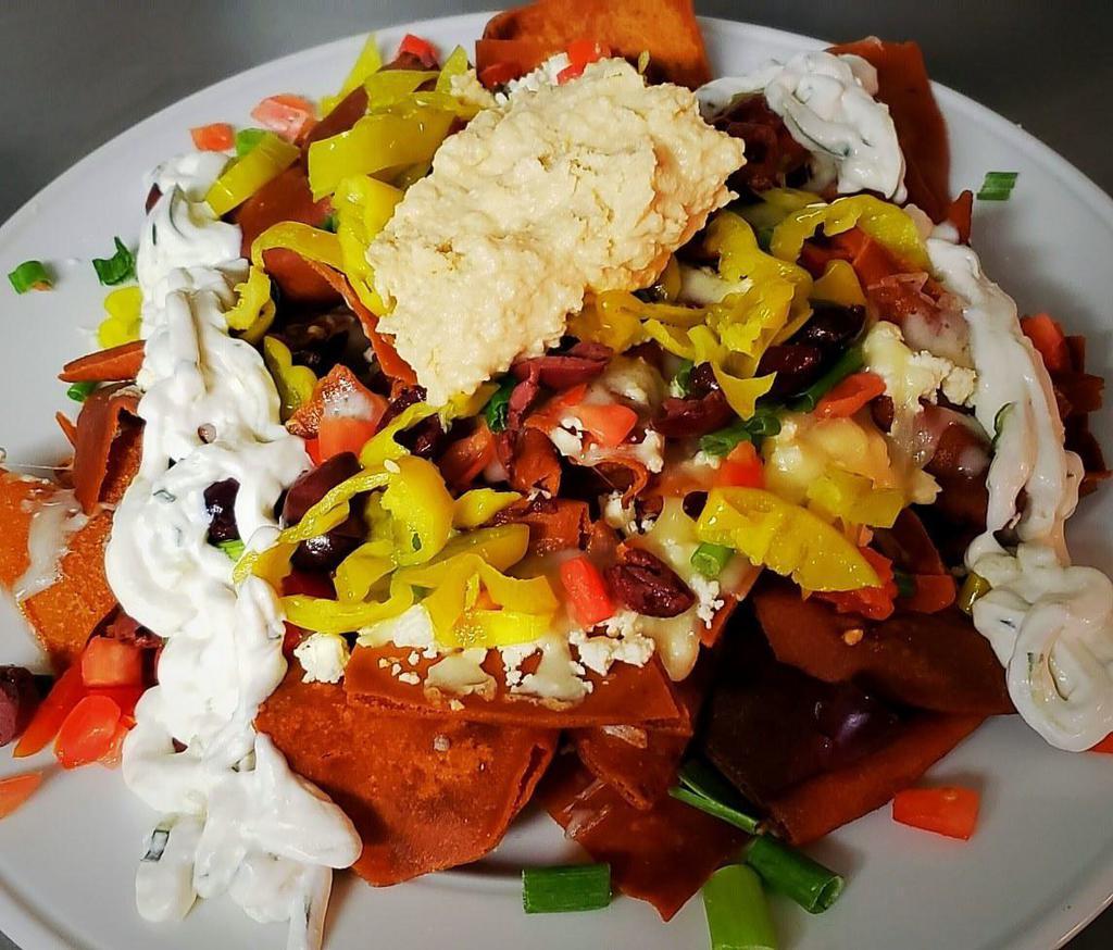 Mediterranean Nacho Platter · Crispy pita chips topped with feta cheese crumbles, diced tomatoes, pepperoncini peppers, Kalamata olives, green onions, drizzled with tangy tzatziki sauce, and a dip of hummus. Add chicken and beef for an additional charge.