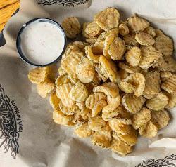 Fried Pickles · Sliced crinkle cut pickle chips, lightly breaded and fried golden-brown. Served with Cajun ranch dressing.