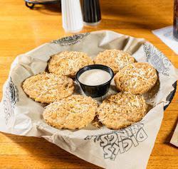 Fried Green Tomatoes · Fresh green tomatoes. Breaded and deep-fried, topped with Parmesan cheese and garlic pepper flakes. Served with Cajun ranch dressing.
