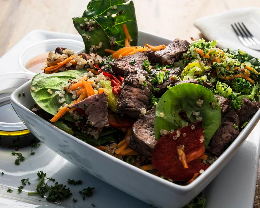 Steak Bowl · A bed of leafy greens topped with our house seasoned organic quinoa. Loaded with roasted colored bell peppers, baby spinach and broccoli then sliced in house grass finished steak garnished with parsley.
