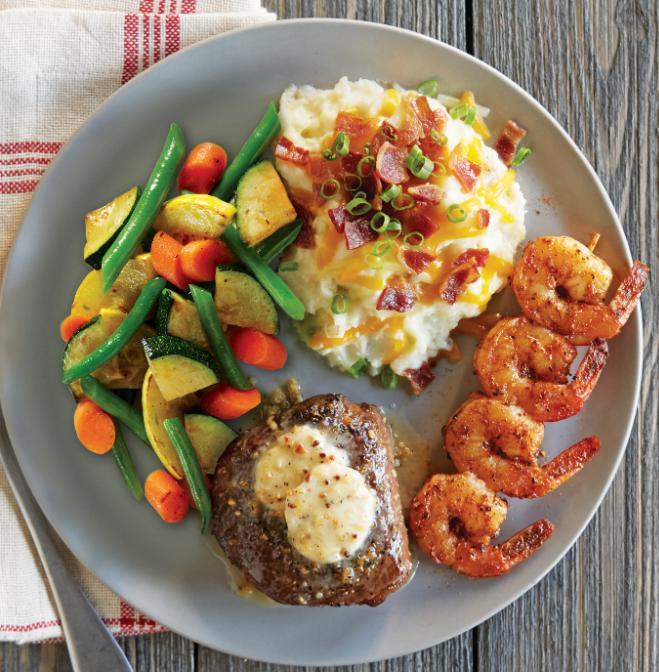 Top Sirloin & Shrimp Combo · Seasoned and seared 6 oz. steak topped with house-made roasted garlic butter and paired with a Cajun-spiced skewer of tender shrimp. Served with loaded mashed potatoes and fresh seasonal vegetables.