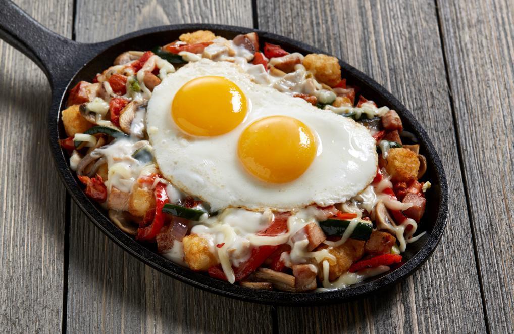 Farmhouse Skillet · Diced ham, mushrooms, oven-roasted tomatoes, fresh vegetables and two eggs any style, with pepper jack cheese and spicy poblano cheese sauce served over crispy tots.