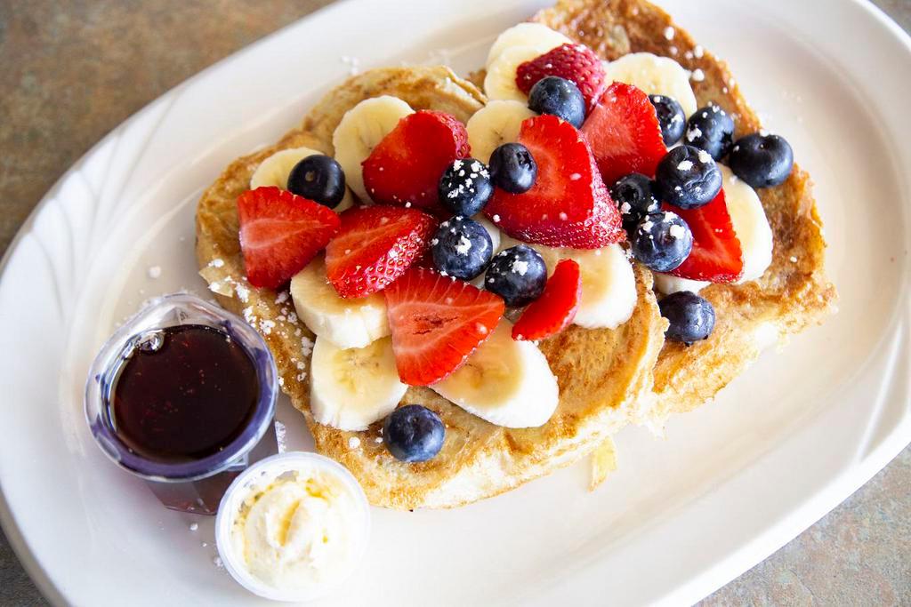 Florida French Toast · Two slices of sourdough bread dipped in a rich custard batter and grilled golden topped with powdered sugar and covered in blueberries, strawberries, and bananas (raisin bread available as an alternative.