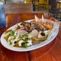 Chilaquiles · Fried tortilla triangle simmered in red or green salsa. Your choice of meat. Topped with che...