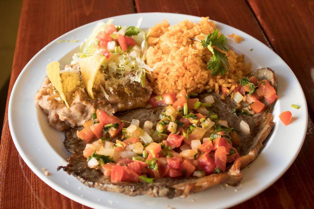 Bistec a la Mexicana · Strip of steak cooked in a tomato sauce, with onion and cilantro. Served with rice, beans, and tortillas.