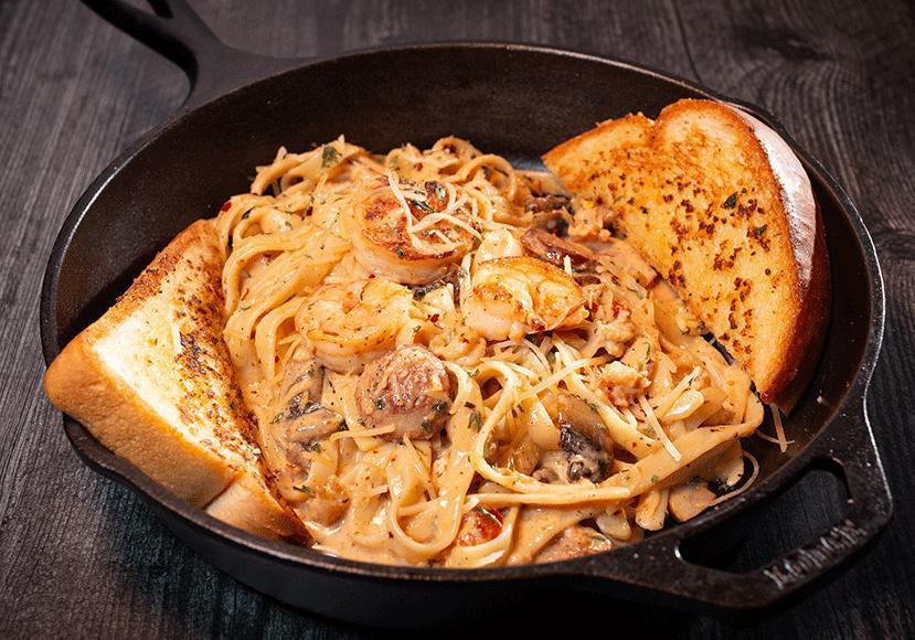 Pasta Mardi Gras · Creamy fettuccine noodles smothered in our zesty Alfredo sauce with shrimp, crawfish, sausage, mushroom, tomato, and Cajun spice, seasoning and a side of garlic toast.