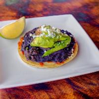 Queso y Frijoles Taco · Blend of asadero y Cotija, black bean puree, chipotle salsa, avocado. Served on racquets whi...