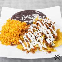 Pastor Chilaquiles · Marinated pork, eggs, tomato, onion, mexican rice, refried black beans, sour cream, queso fr...