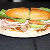 Torta Cubana · Meat: Carnitas, chorizo and ham in a hot french roll with melted cheese, mayonnaise, sour cr...