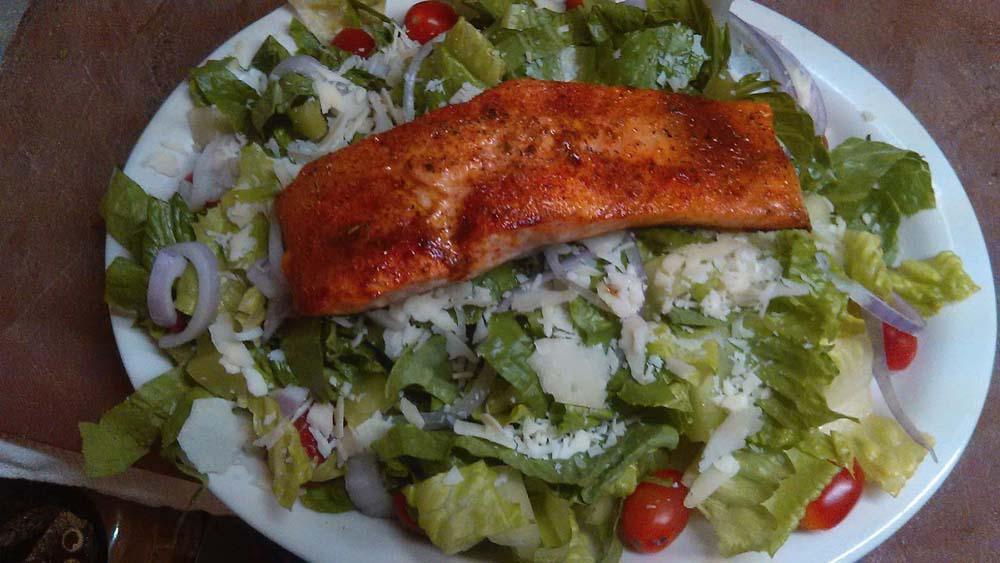 Salmon Caesar Salad · Broiled Cajun salmon on romaine lettuce with Caesar dressing.