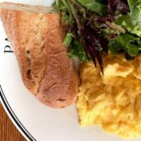 Scrambled Eggs · Three eggs scrambled, served with a side of fresh greens, and baguette slice.