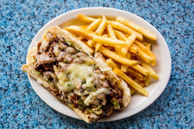 Philly Cheesesteak · Steak or chicken, grilled onions and green peppers, melted provolone, topped with queso on a hoagie. “All The Way” includes lettuce, tomato, and mayo.