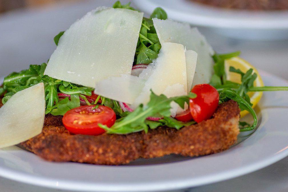 Milanese · Pork chop milanese served with arugula, tomatoes and shaved Parmigiano Reggiano