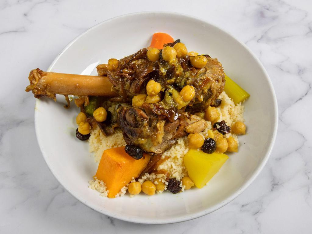Lamb Shank Couscous · slow-cooked lamb shank, braised butternut squash, carrots, zucchini, celery, turnips, served over a bed of fluffy couscous, topped with chickpeas, raisins, & caramelized onions