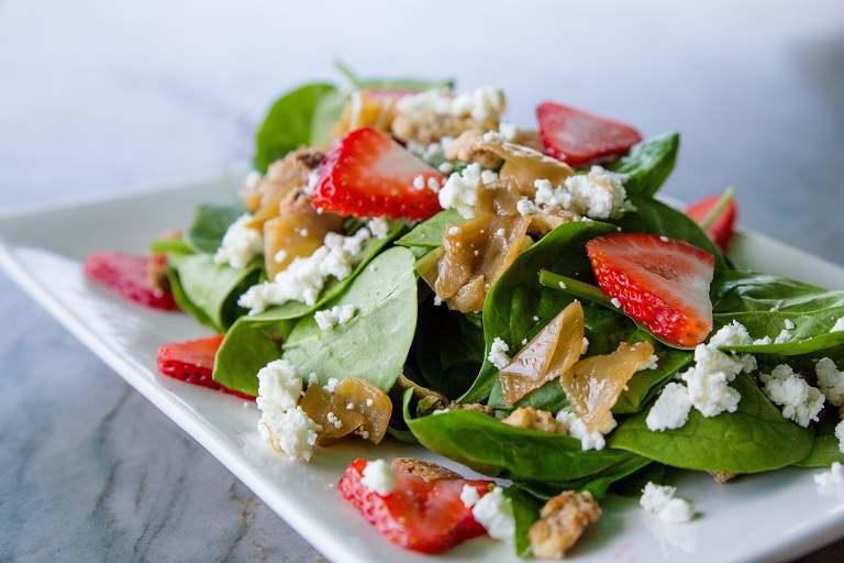 Spinach Salad · Fresh spinach, caramelized onions, candied walnuts, goat cheese, seasonal berries mixed with a honey champagne vinaigrette.