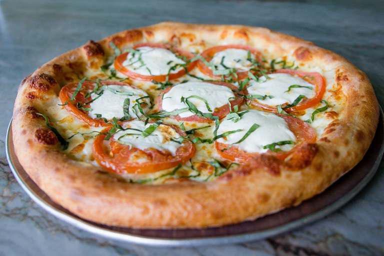 Margherita Pizza · Fresh sliced tomatoes, house-made fresh mozzarella, roasted garlic, fresh basil, with a herb-flavored virgin olive oil.