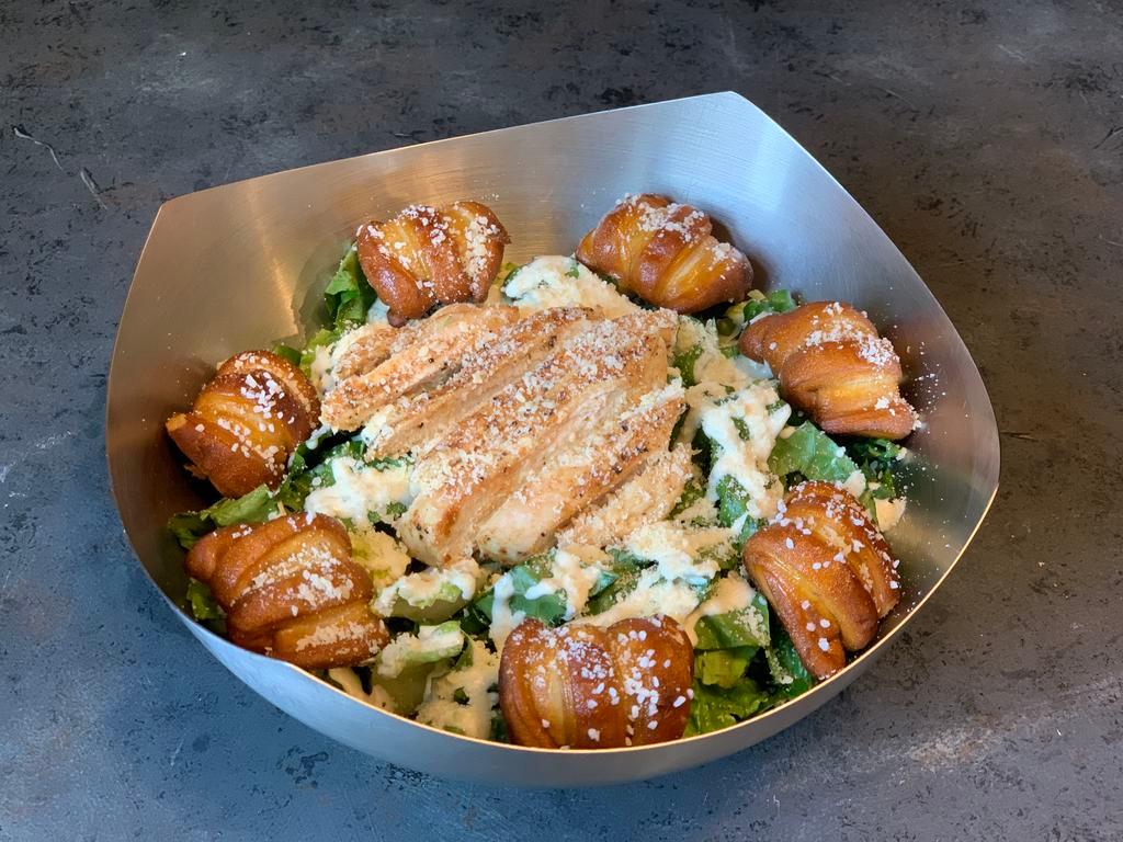 Chicken Caesar Salad · Freshly chopped romaine lettuce and grilled chicken breast drizzled with smoky Caesar dressing and garnished with Parmesan cheese-crusted pretzel croutons.