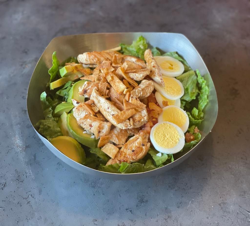 Cobb Salad · Grilled chicken on freshly chopped romaine lettuce with avocado slices, hard-boiled eggs, diced tomatoes, bacon bits and shredded mozzarella cheese. Topped with seasoned tortilla crunchies.