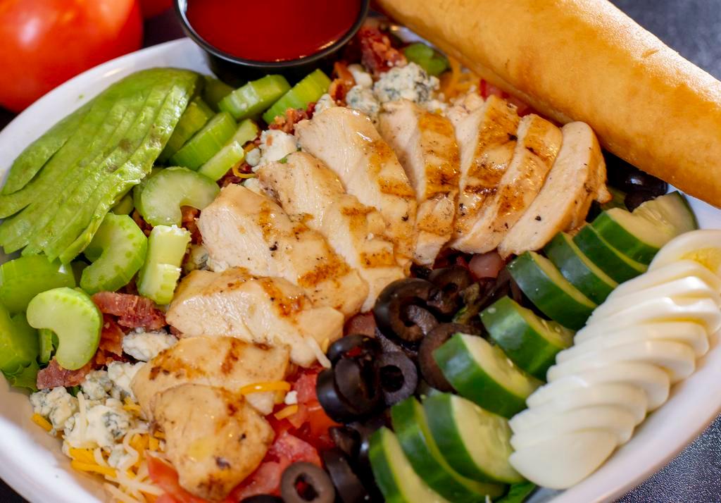 Chicken Cobb Salad · Mixed greens topped with grilled chicken, bleu cheese crumbles, smokehouse bacon, fresh avocado, tomatoes, cucumbers, eggs, black olives, celery and cheddar Jack cheese. Served with your choice of dressing.