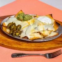 Nachos El Ranchero · Tortilla chips covered with refried beans and melted cheese. Topped with sour cream guacamol...