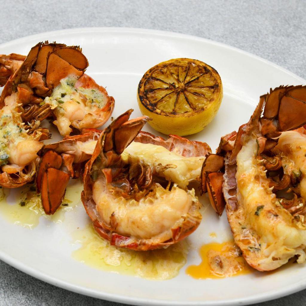 Petite Lobster Tail Trio · 3 petite cold water lobster tails broiled, sriracha tomato butter, almond herb butter, uni butter, grilled lemon.