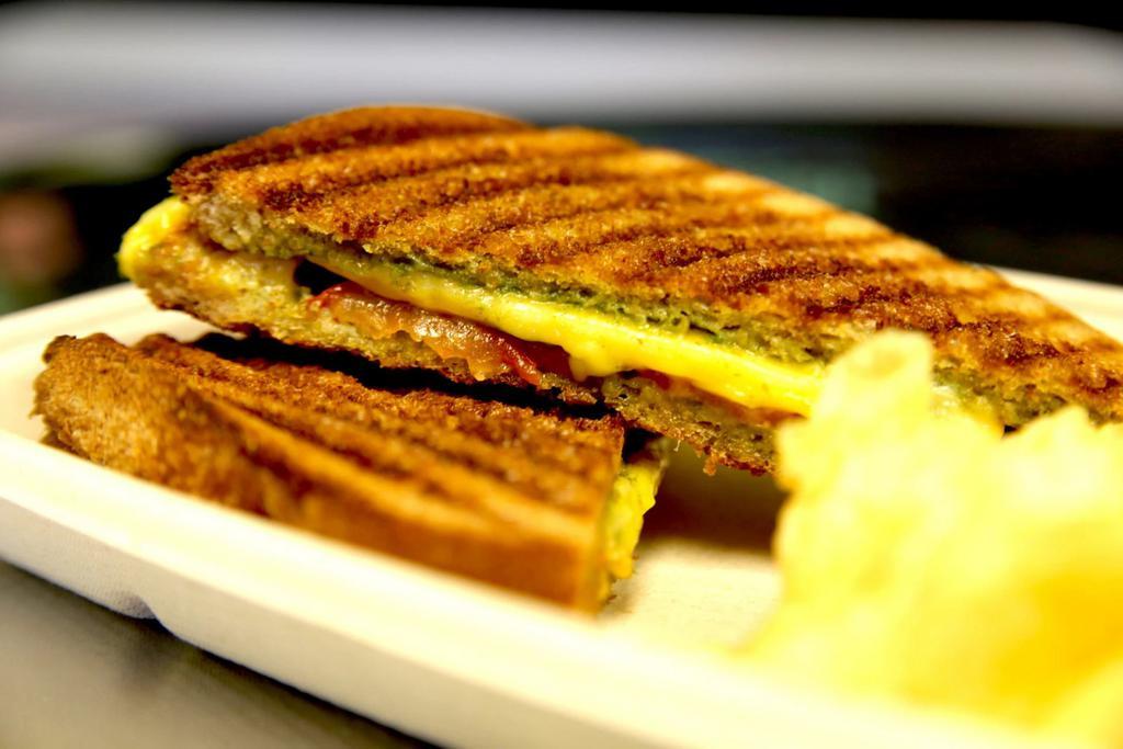 Grilled Cheese Panini with Pesto and Tomato · Vegan provolone and cheddar cheese, fresh pesto and sliced tomato on grilled wheat bread. Served with a choice of mixed field greens, lime corn chips or kettle chips. Soy free.