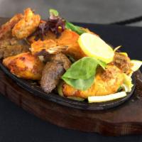 66. Mixed Tandoori · Combination of marinated chicken, lamb, shrimp and salmon, served on a sizzling platter with...