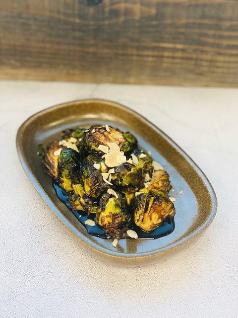 Bruselas · Crispy brussels sprouts, yuzu vinaigrette & toasted almonds. 
Contains: nuts.