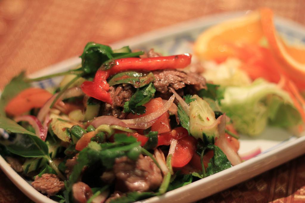 23. Yum Nuer · Beef salad. Gluten-free. Choice of spice level. Beef salad mixed with onions, chili, mushroom, cucumber, basil, and tomatoes in lime dressing serves with iceberg lettuce.
