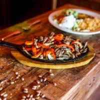 Fajitas Rancheras · Served on a bed of bell peppers, tomatoes, and onions accompanied by Mexican rice, refried b...