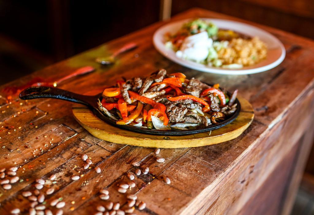 Fajitas Rancheras · Served on a bed of bell peppers, tomatoes, and onions accompanied by Mexican rice, refried beans, sour cream, guacamole, and pico de gallo. Choice of flour or corn tortillas.