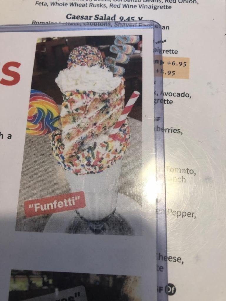 FunFetti Shake · Frosted Glass with Rainbow Sprinkles,Topped with FunFetti Cake, Whipped Cream, a Sour Belt, and a Cake Pop