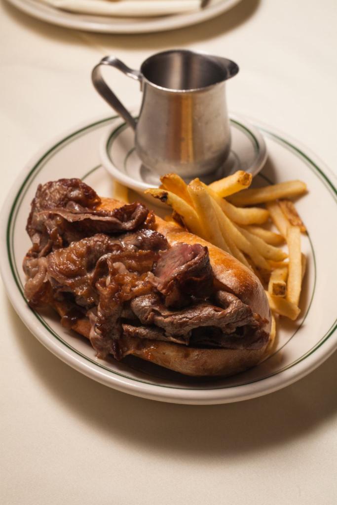 Dry Aged Dip · Shaved rib eye, mushrooms and onions, beef au jus and french fries.