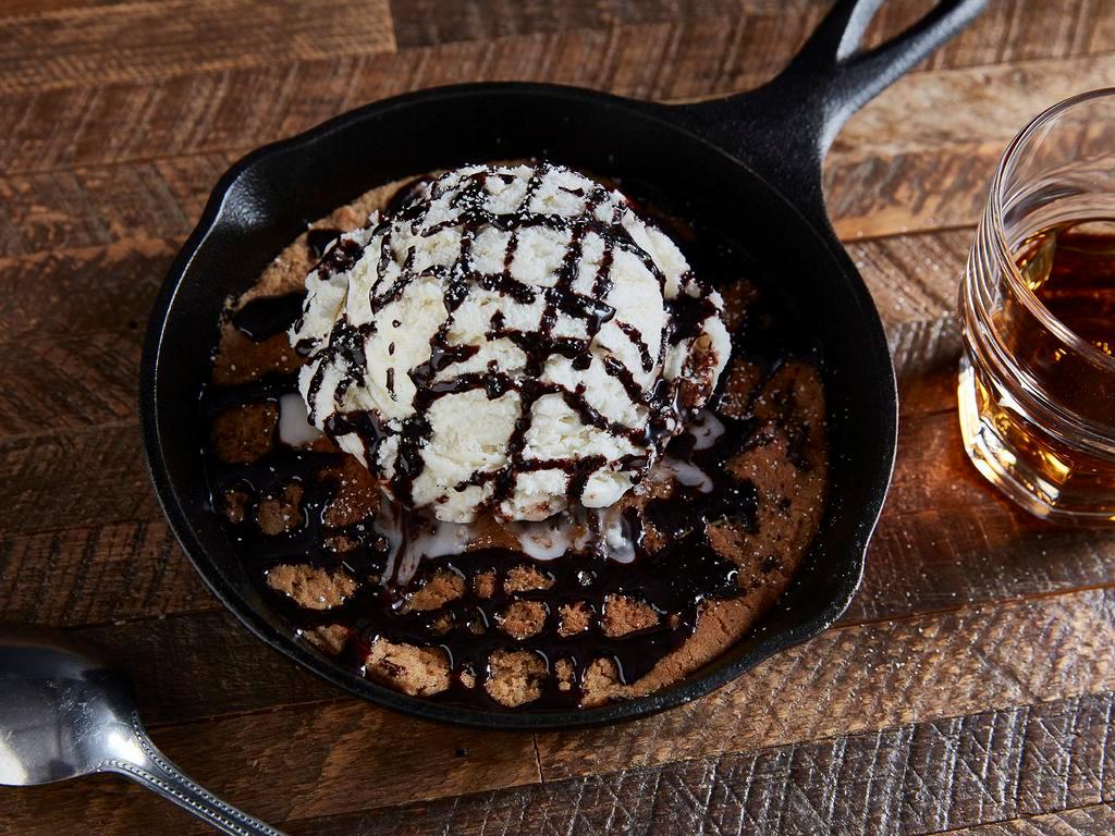 Titled Guilt Chocolate Chip · Hot, fresh baked chocolate chip cookie topped with vanilla ice cream, powdered sugar and chocolate sauce.
