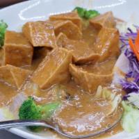 Orchid Tofu · Sliced fried tofu with signature peanut sauce and coconut milk on a bed of steamed vegetables.