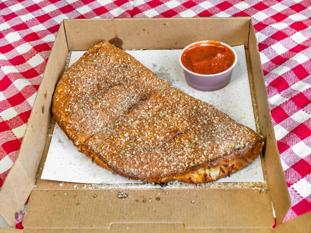 Philly Cheesesteak Calzone · Fresh pizza dough stuffed with two layers of mozzarella, philly steak, white onion, green pepper topped with butter, garlic, Parmesan Romano, and mayo.