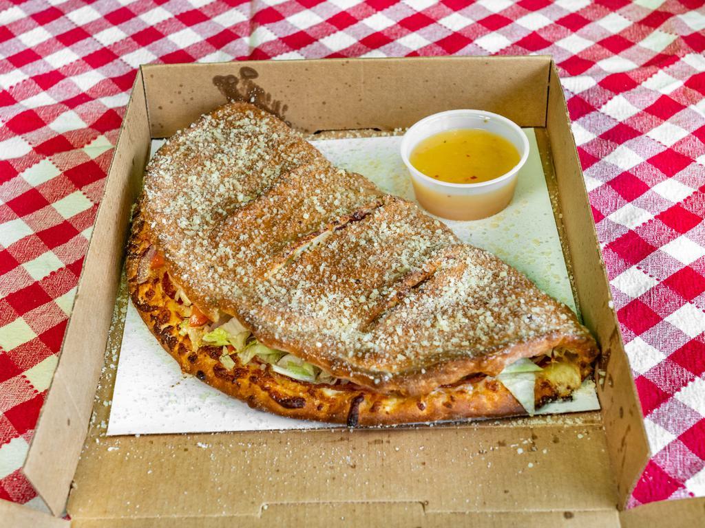 The Soprano Calzone · Fresh pizza dough stuffed with two layers of mozzarella, ham, salami, pepperoni, banana peppers, red onion, lettuce, tomato topped with butter, garlic, and Parmesan Romano. Served with a side of Italian dressing.