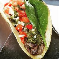 Steak Taco · Grilled steak, cilantro chimichurri, tomato, grilled onions, cheese and lettuce.