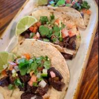 Tejas Street Tacos · 3 KC steak tacos topped with onions and cilantro. Served with limes and 2 sides. Add pico an...