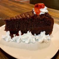 Chocolate Cake · Chocolate rich slice of cake with whipping cream on the sides, a hint of strawberry sauce an...