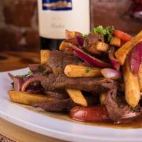 Lomo Saltado  · Traditional Peruvian stir-fry, seasoned strips of steak, onions and tomatoes, served with cr...