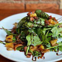 Insalata Pisticci · bed of baby spinach tossed with crispy potatoes and pancetta lardons, drizzled with a balsamic reduction