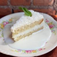 Fresh Coconut Cake · Feather light white cake with a rich coconut flake frosting garnished with berries and mint.