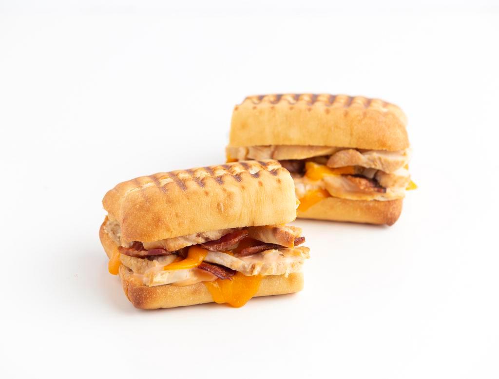 Turkey, Cheddar 'n Bacon Panini · Gobble . . . Gobble! This Panini Melt features our Roasted Turkey, Smoky Bacon and melty-cheesy Cheddar Cheese. It's topped with Thousand Island dressing and served warm between two slices of butter-toasted Ciabatta bread.