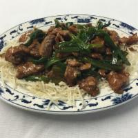 Mongolian Beef · Sliced beef dry sauteed with fresh scallions in brown sauce served over rice noodle bedding.