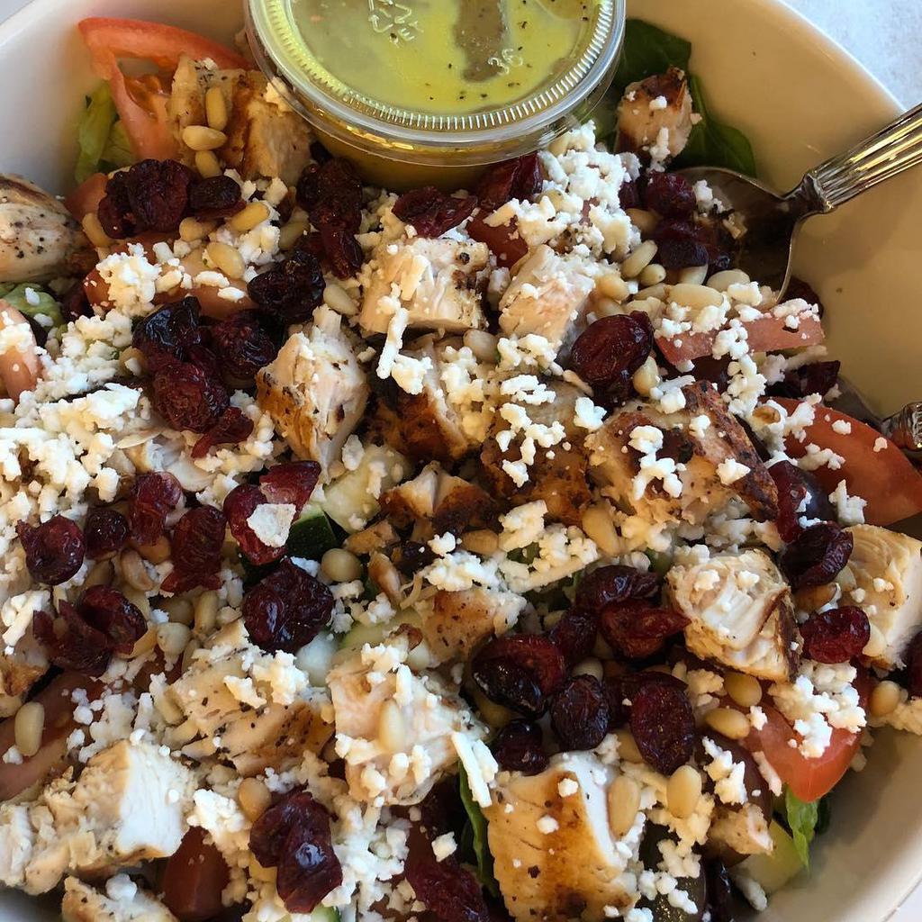 Taza Chicken Salad · Chopped spinach and romaine, yellow squash, zucchini, grapes, tomatoes, and chopped grilled chicken tenders tossed with honey dijon dressing and topped with feta, dried cranberries, and lightly fried pine nuts. Nuts, gluten free.