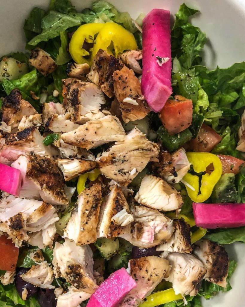 Greek Chicken Salad · Chopped spinach and romaine, Lebanese salata, calamata olives, banana peppers, and chopped, grilled chicken tenders tossed with Aladdin's dressing and topped with feta and pickled turnips. Gluten-free.