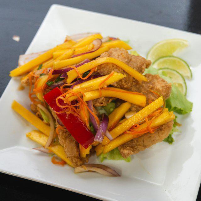 Pla Tod Yum Ma Muang · Fried filet fish served with mango salad, shredded mango, shallots, scallions, and cashew nuts in a juicy lime dressing.