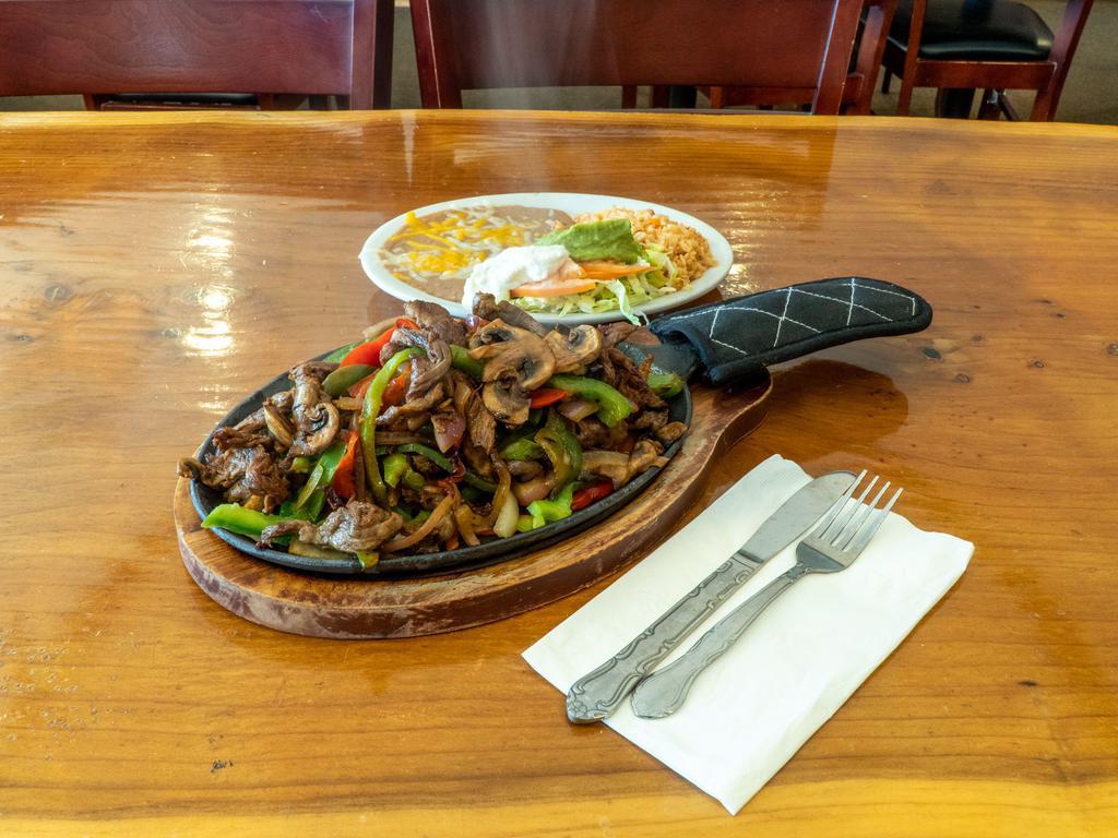Sizzling Steak Fajitas · Stir-fried tender marinated steak with bell peppers, mushrooms and onions cooked in a unique blend of spices. Served with guacamole and sour cream.